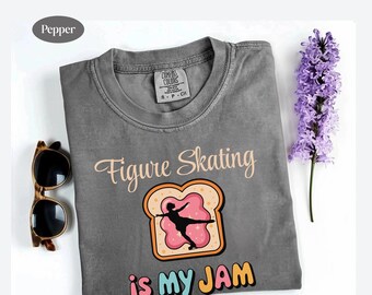 May include: Gray t-shirt with the text "Figure Skating is my JAM" and a graphic of a figure skater on a piece of toast. The shirt also features a pair of sunglasses and a sprig of purple flowers.