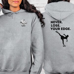 May include: Gray hooded sweatshirt with a figure skater graphic and the text "NEVER. LOSE. YOUR EDGE." on the back. The front of the sweatshirt has a pair of ice skates and the name "Sophia" printed on it.