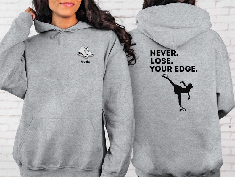 May include: Gray hooded sweatshirt with a figure skater graphic and the text "NEVER. LOSE. YOUR EDGE." on the back. The front of the sweatshirt has a pair of ice skates and the name "Sophia" printed on it.