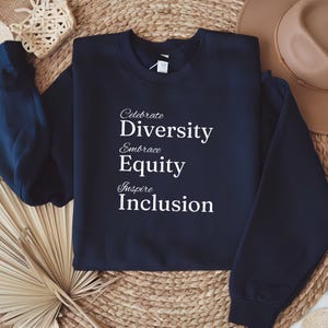 May include: Navy blue sweatshirt with white text that reads "Celebrate Diversity Embrace Equity Inspire Inclusion".