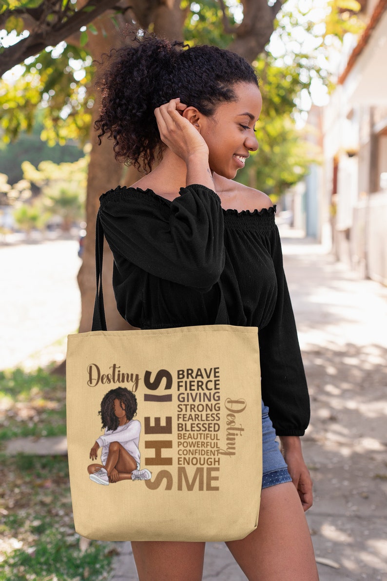 Pu&ograve; includere: Una borsa tote beige con un'illustrazione marrone di una donna e il testo "Destiny SHE IS BRAVE FIERCE GIVING STRONG FEARLESS BLESSED BEAUTIFUL POWERFUL CONFIDENT ENOUGH ME Destiny".