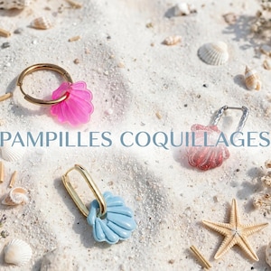 Könnte beinhalten: Drei Creolen mit muschelförmigen Anhängern in Pink, Rot und Hellblau. Der pinke Anhänger hängt an einem goldenen Ring, der rote an einem silbernen strukturierten Ring und der hellblaue an einem ovalen goldenen Ring. Text PAMPILLES COQUILLAGES.