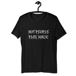 May include: Black t-shirt with white text that reads "HOT PEOPLE PLAY MAGIC" in a stylized font.