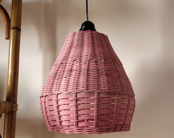 Puede incluir: Una lámpara colgante de mimbre rosa con un cable y un casquillo negros.