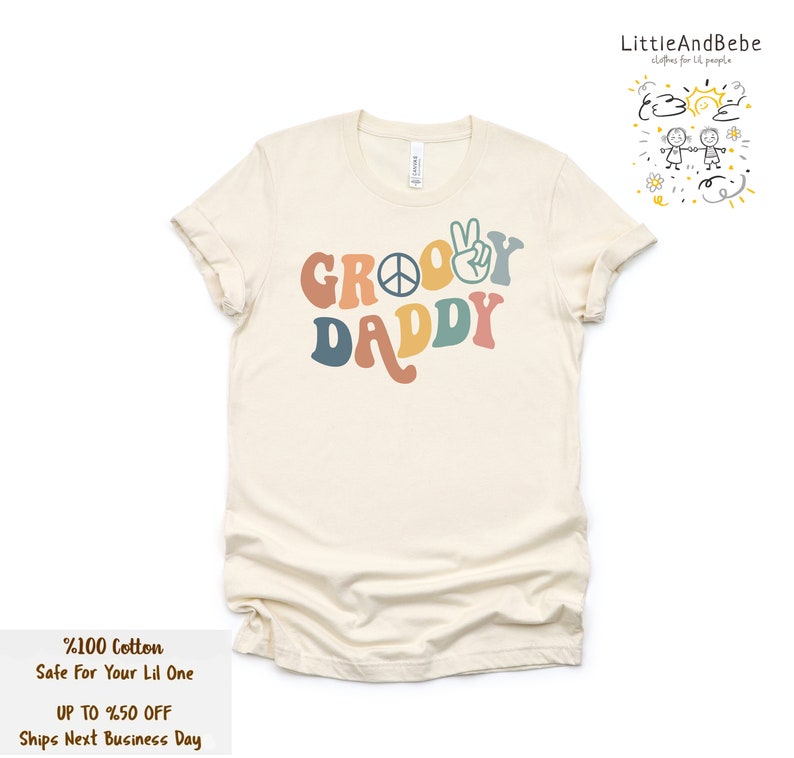 May include: A beige t-shirt with the text "Groovy Daddy" in rainbow colors. The text includes a peace sign and a peace hand gesture.