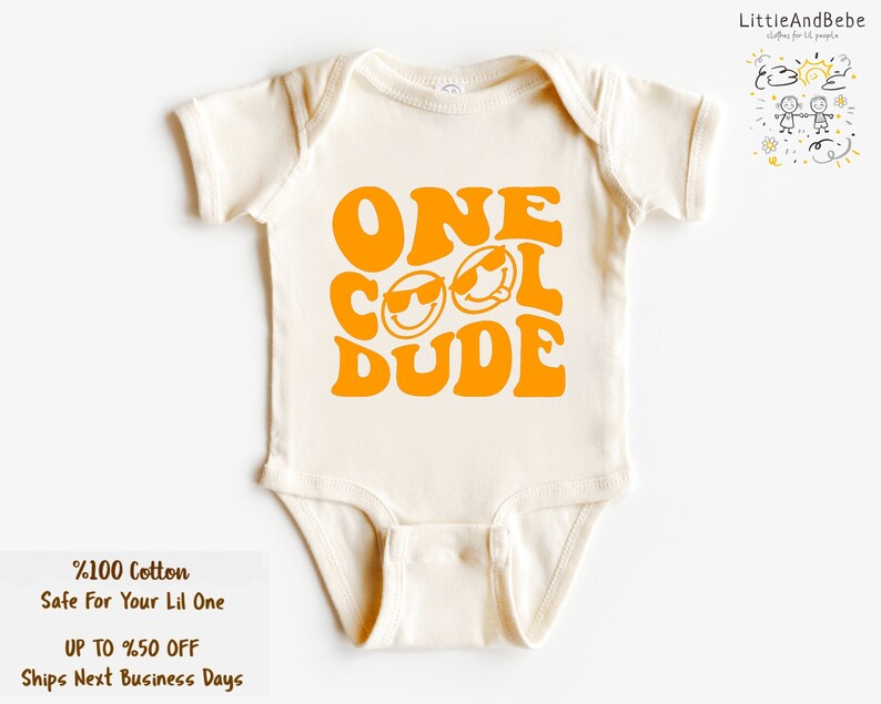 May include: A white baby onesie with a yellow graphic that says "ONE COOL DUDE" in a retro font. The graphic includes two smiley faces with sunglasses.