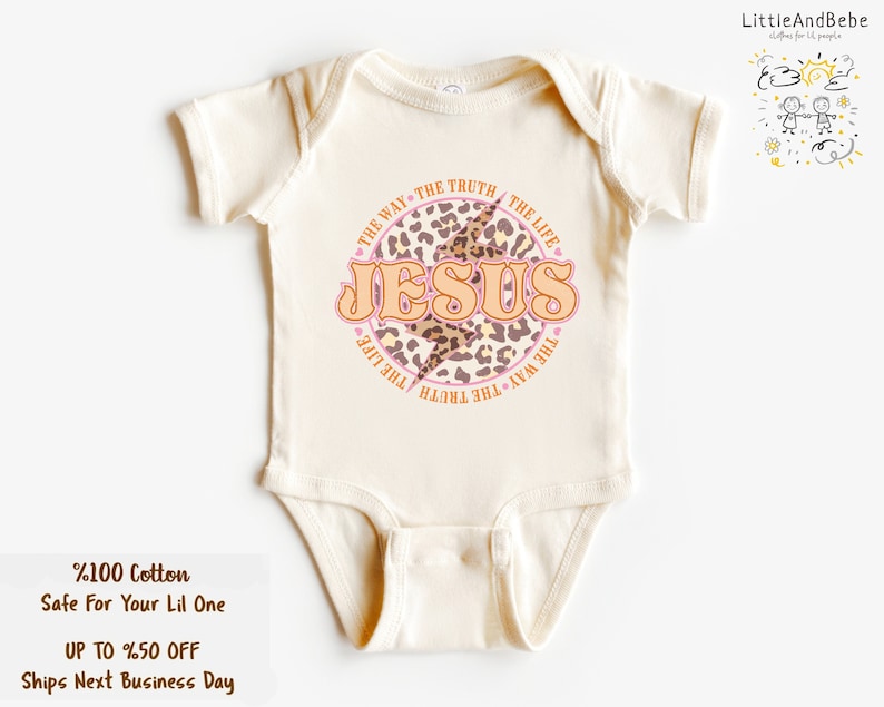 May include: A white baby onesie with a pink and brown leopard print circle design. The circle has the words "THE WAY THE TRUTH THE LIFE" around the outside and "JESUS" in large letters inside the circle.