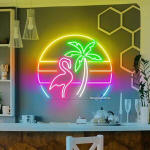 Puede incluir: Un letrero de ne&oacute;n con un flamenco rosa y una palmera en una puesta de sol arco&iacute;ris. El letrero est&aacute; colgado en una pared con un patr&oacute;n de azulejos hexagonales marrones. Dos taburetes de bar blancos est&aacute;n en primer plano.