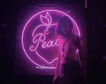 May include: A neon sign in the shape of a peach with the word "Peace" inside. The sign is on a wall with a leopard print pattern. A person is standing in front of the sign, wearing a pink top and a black skirt.