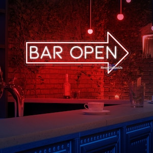 Puede incluir: Una pared de ladrillo rojo con un letrero de neón que dice "BAR OPEN" con una flecha roja apuntando hacia la derecha. El letrero está iluminado y hay luces colgando del techo.