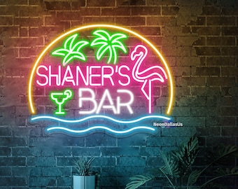 May include: Neon sign with a pink flamingo, palm trees, and a margarita glass. The sign says "Shaner's Bar" in a yellow, pink, and blue neon font.