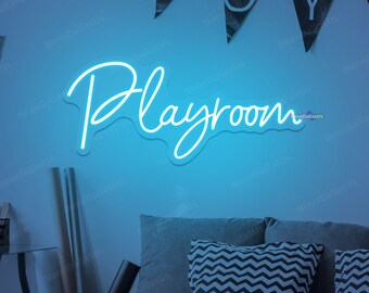 May include: A blue neon sign with the word "Playroom" in a cursive font. The sign is mounted on a light blue wall with a bed in the background.