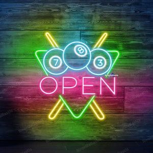 Può includere: Segno al neon con un triangolo da biliardo, tre palle da biliardo e due stecche incrociate. Il segno dice "APERTO" in lettere al neon rosa.