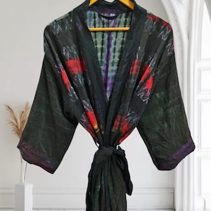 Może przedstawiać: Czarna jedwabna szlafrok z kolorowym wzorem tie-dye. Szlafrok ma długi, płynny krój i szeroki, wygodny kołnierz.