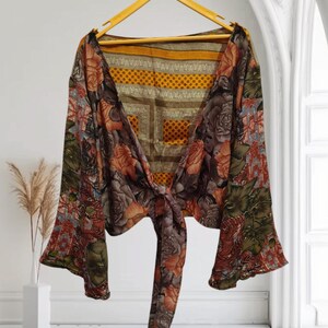 May include: A brown and green floral print top with a tie front and bell sleeves. The top is made of a lightweight fabric and has a relaxed fit.