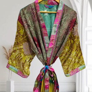 May include: A green, pink, and gold silk robe with a floral pattern. The robe has a tie belt and long sleeves.