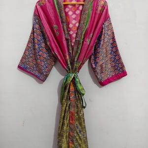 May include: A pink, green, and blue silk robe with a floral pattern. The robe has a tie belt and is made of a soft, flowing fabric.