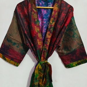 May include: A colorful silk robe with a tie belt. The robe has a patchwork design with shades of red, green, brown, and purple. The tie belt is green with yellow and brown accents.