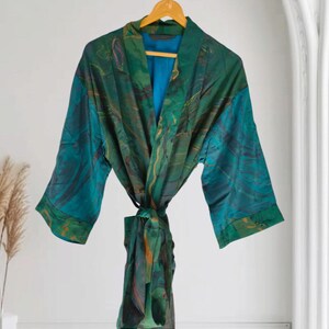 Può includere: Una vestaglia a maniche lunghe con un motivo marmorizzato nei toni del verde smeraldo, ottanio e blu scuro con sottili accenti dorati. Il capo presenta una cintura in vita coordinata e una fodera interna di colore blu a tinta unita.