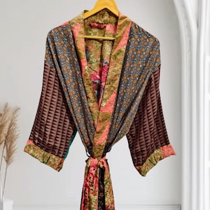 May include: A lightweight kimono-style robe featuring a patchwork design with various patterns including small floral prints in blue, green, and pink, alongside brown geometric triangular motifs on the sleeves, finished with a matching fabric tie belt.
