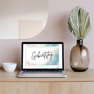 May include: A laptop computer displaying a digital birthday card with a blue and gold watercolor background and the text "Geburtstag".