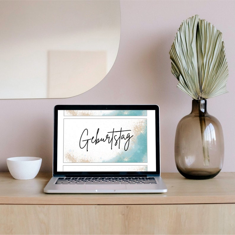 May include: A laptop computer displaying a digital birthday card with a blue and gold watercolor background and the text "Geburtstag".