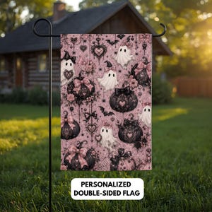 Könnte beinhalten: Eine rechteckige Gartenflagge mit einem altrosa Hintergrund und einem wiederkehrenden Muster aus schwarzen Kürbissen, weißen Geistern, Fledermäusen und herzförmigen Ornamenten. Das Design enthält rosa Schleifen. Text: PERSONALIZED DOUBLE-SIDED FLAG.