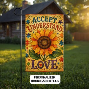 May include: A rectangular garden flag featuring a large yellow sunflower in the center. The text reads ACCEPT UNDERSTAND LOVE. The background is yellow with colorful puzzle pieces and decorative swirls. The flag hangs on a black metal stand.