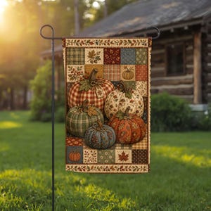 May include: A rectangular garden flag featuring a patchwork design of various autumn-themed patterns, including plaid, polka dots, and botanical prints. The center displays a cluster of five pumpkins in shades of orange, green, and cream.