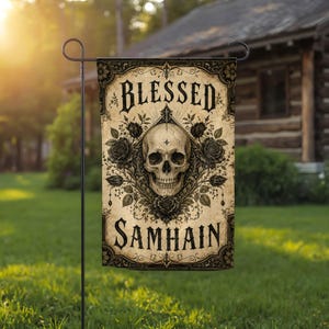 May include: A rectangular garden flag featuring a beige background with a central human skull illustration surrounded by black roses and ornate filigree. The text BLESSED is printed in black at the top and SAMHAIN is printed in black at the bottom.