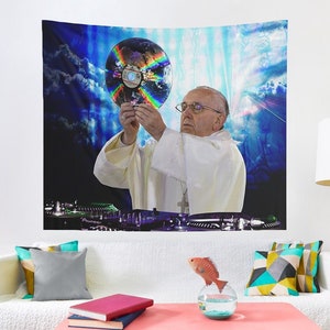 Könnte beinhalten: Ein Mann in einem weißen Gewand hält eine regenbogenfarbene CD vor einem blauen und weißen Hintergrund. Er steht vor einem DJ-Mixer mit dem Wort "Pioneer" darauf.