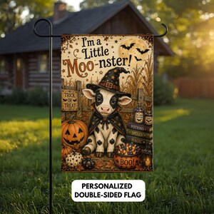 Peut inclure: Un drapeau de jardin rectangulaire représentant un veau noir et blanc portant un chapeau de sorcière et une cape. Le texte indique I'm a Little Moo-nster! avec une citrouille, un bol de bonbons étiqueté BOO et des livres intitulés Potions, Spells, Magic.