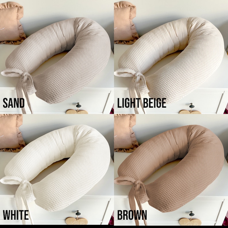 May include: Four waffle-textured pregnancy pillows in different colors: sand, light beige, white, and brown. Each pillow has a tied ribbon at the end.
