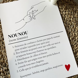 May include: A black and white line drawing of two hands holding each other. The text "NOUNOU (nom f&eacute;minin)" is at the top of the image. The text below the drawing defines the word "NOUNOU" as a person of trust chosen by parents to help a child grow. The text also describes the qualities of a "NOUNOU" as being a caring, loving, and supportive person. A red heart is in the bottom right corner of the image.