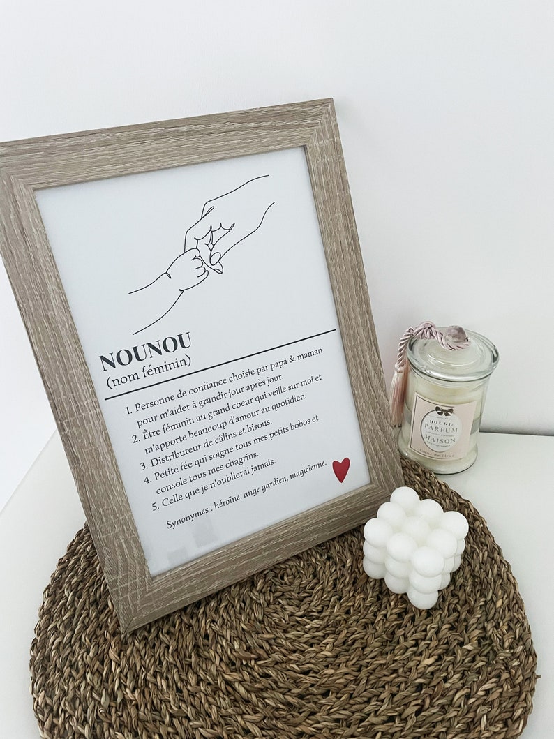May include: A black and white line drawing of two hands holding each other. The text below the drawing defines the word "Nounou" as a noun, meaning a person of trust chosen by parents to help a child grow. The text also describes the qualities of a "Nounou" as a caring, loving, and supportive person.