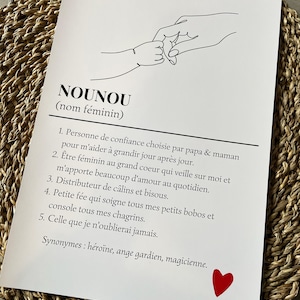 May include: A black and white line drawing of two hands holding pinkies, with the word "NOUNOU" (meaning "nanny" in English) written in black text below the drawing. The text defines the word "NOUNOU" as a person of trust chosen by parents to help a child grow, a caring and supportive person, a giver of hugs and kisses, a comforter of hurts and sorrows, and someone who will always be remembered. The text ends with the word "magicienne" (meaning "magician" in English) and a red heart.