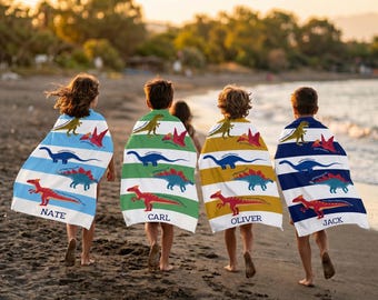 May include: Four rectangular beach towels featuring horizontal stripes and dinosaur illustrations in green, blue, and red. Each towel displays the names Nate, Carl, Oliver, and Jack in dark blue text at the bottom, draped over the backs of four children.