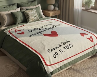 May include: A cream-colored fleece blanket designed like an ace of hearts playing card. It features red heart symbols, the text Lucky in love, wrapped together, and the names Emma & Jack with the date 09.11.2025 printed in black script.