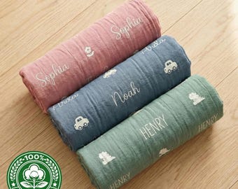 May include: Three rolled cotton baby blankets in pink, blue, and green. Each blanket is embroidered with a name and a small graphic. The pink blanket has the name "Sophia" and a flower. The blue blanket has the name "Noah" and car graphics. The green blanket has the name "Henry" and a dinosaur graphic.