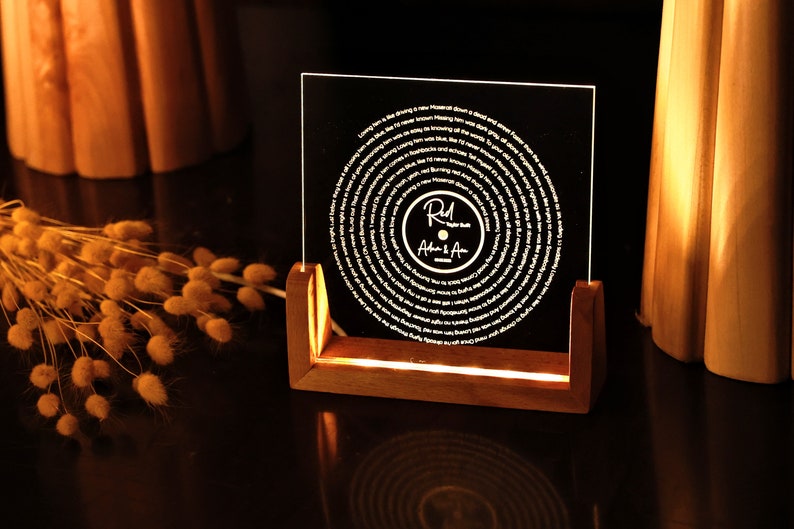 May include: A wooden stand with a clear acrylic plaque featuring a circular design with a record-like spiral pattern. The plaque has the text "R.M. After A" in white lettering.