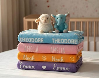 May include: A stack of four folded fleece blankets in blue, pink, orange, and purple. The blue blanket features the name THEODORE, the pink blanket says AMELIA, the orange blanket says Noah with sun icons, and the purple blanket says Emma with a heart.