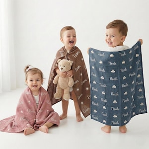 May include: Three smiling children with personalized blankets. One child is wrapped in a pink blanket with the name "Olivia" printed on it. Another child is wrapped in a brown blanket with the name "Liam" printed on it. The third child holds a blue blanket with the name "Noah" printed on it.