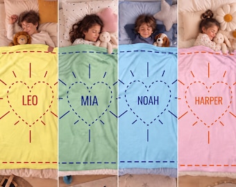 May include: A collection of four soft fleece blankets in yellow, light green, light blue, and light pink. Each blanket features a central dashed-line heart graphic with the names LEO, MIA, NOAH, and HARPER printed in the center.
