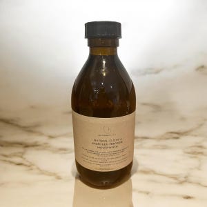K&ouml;nnte beinhalten: Eine braune Glasflasche mit schwarzem Verschluss und einem braunen Papier-Etikett. Das Etikett lautet "The Warmway Way Natural Clove & Hydrogen Peroxide Mouthwash".