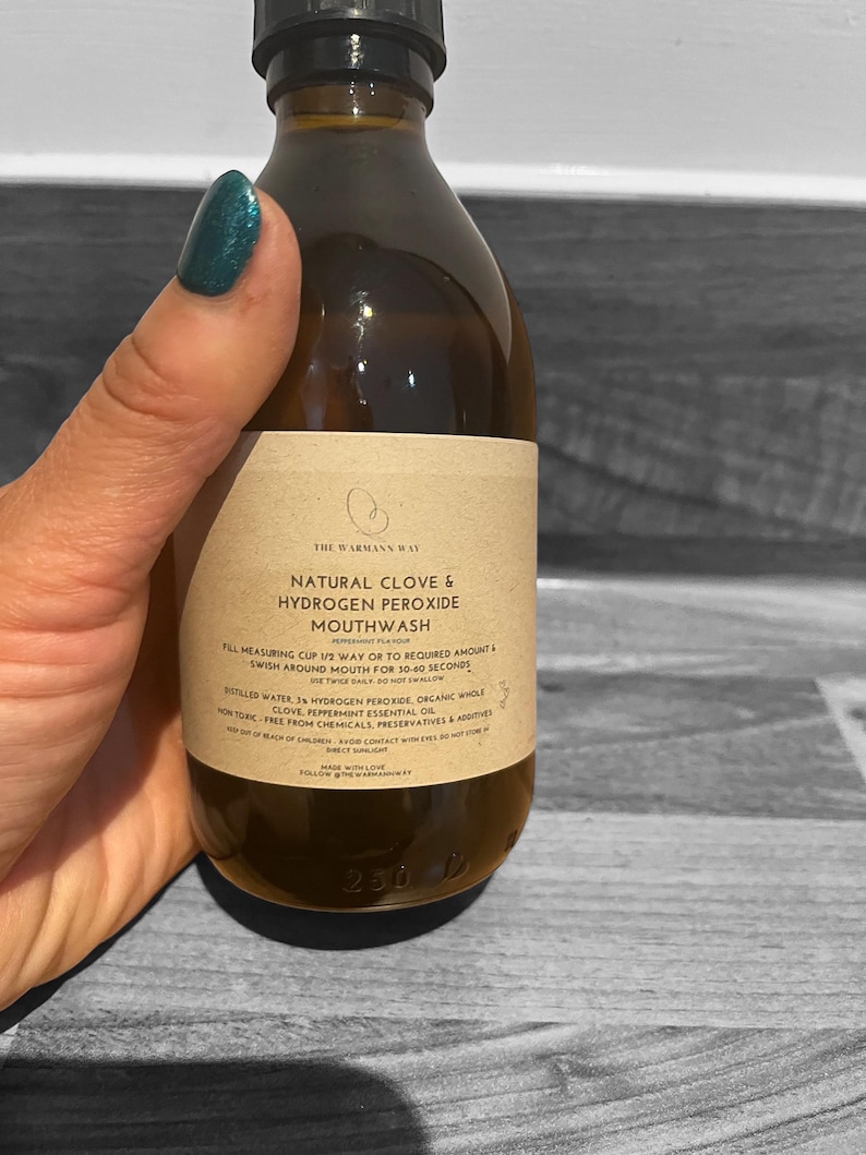 Op de afbeelding: Een bruine glazen fles met een etiket waarop "The Warmann Way Natural Clove & Hydrogen Peroxide Mouthwash" staat. Het etiket bevat ook gebruiksaanwijzingen, ingredi&euml;nten en waarschuwingen. De fles is 230 ml.