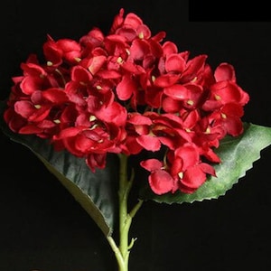 May include: A single stem of artificial red hydrangea flowers with green leaves.
