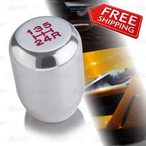 May include: A chrome-finished shift knob with red gear pattern markings. The top of the knob displays the gear pattern: 1, 3, 5, R, 2, and 4. The knob has a smooth, rounded shape. The image includes a red tag that says "FREE SHIPPING".