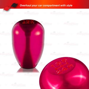 May include: A shiny, magenta-colored car shift knob. The top of the knob has the gear pattern etched in a darker shade of magenta. The text "Overhaul your car compartment with style" is at the top of the image.