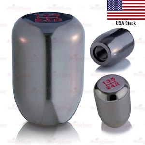 May include: A silver-colored car gear shift knob with red gear markings. The knob has a cylindrical shape with a rounded top. The image also shows a USA flag and the text "USA Stock".