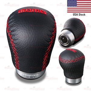 May include: Black leather shift knob with red stitching and the word "momo" in red. The shift knob has a silver base and is shown from multiple angles. The text "USA Stock" is visible in the image.